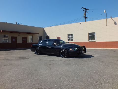 2003 Ford Crown Victoria - Wide shot of a lowered black Crown Victoria with grille guard sitting in an open parking area.