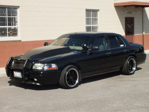 2003 Ford Crown Victoria - Driver-front profile of a slammed black Crown Victoria with grille guard and California plate.