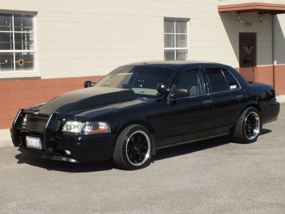 Black Crown Victoria driver-side front view with push bar and billet grille, lowered