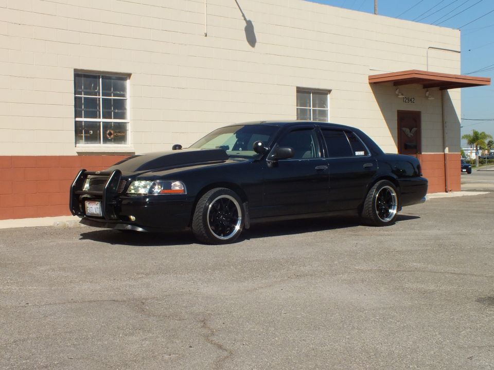 Black Crown Victoria driver-side front quarter with push bar and California plate, lowered