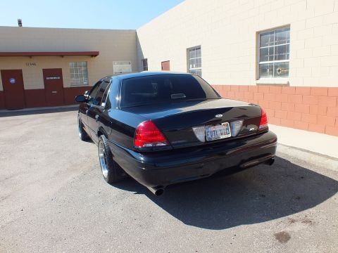 2003 Ford Crown Victoria - Rear view of a black Ford sedan showing dual exhaust and a personalized plate.