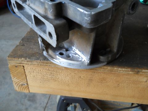 1992 Ford Bronco - Close-up of a metal engine component resting on a wooden surface, with a SuperMotors logo visible at the bottom right.