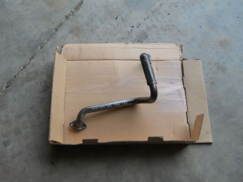 1992 Ford Bronco - A metal exhaust pipe with a flange and a textured end is shown resting in a cardboard box on a concrete floor.
