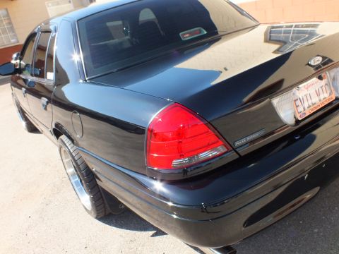 2003 Ford Crown Victoria - Tight rear quarter of a black Ford sedan showing Police Interceptor badge and plate.