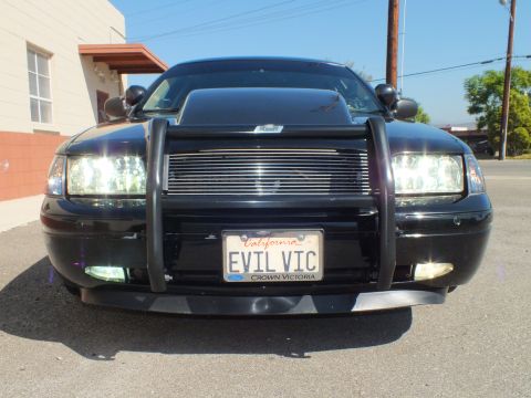 2003 Ford Crown Victoria - Close front view showing billet grille, push bar and a California EVIL VIC license plate over a Crown Victoria badge