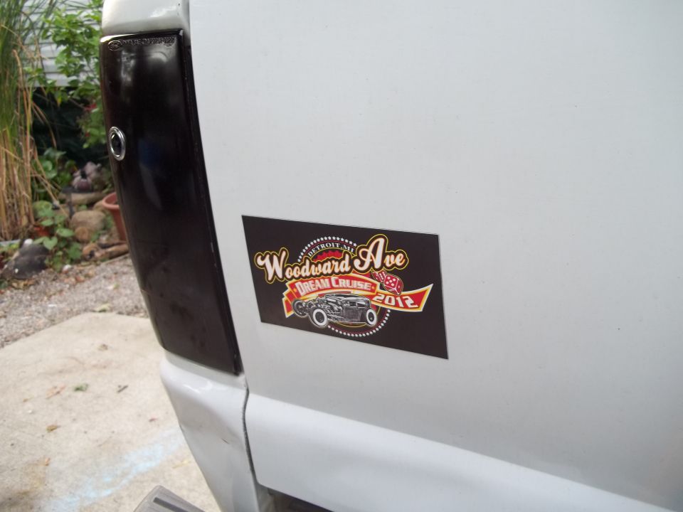 Sticker on white vehicle reads 'Woodward Ave Dream Cruise 2012' with a hot rod graphic