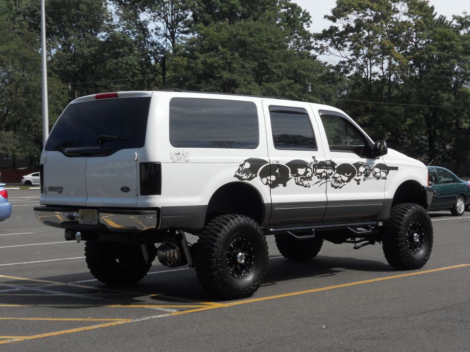 2001 Ford Excursion lifted with large tires and skull graphics on the side