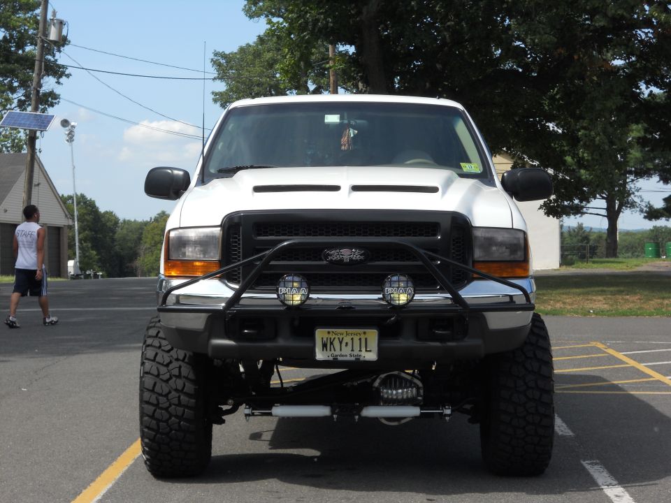 White 2001 Ford Excursion with a black grille guard and off-road tires, viewed from the front