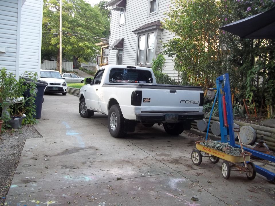 White Ford pickup truck rear view, with a white SUV in the background