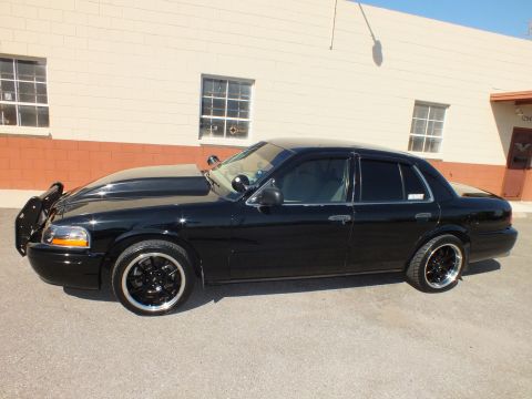 2003 Ford Crown Victoria - Side profile of a lowered black Crown Victoria with front push bar, tinted glass and dark machined wheels