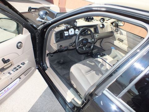 2003 Ford Crown Victoria - Driver-side interior view showing tan upholstery, custom small steering wheel and overhead gauge pods