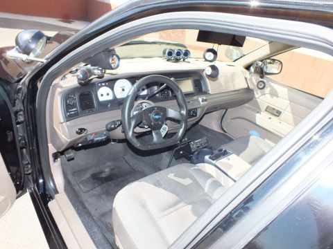 2003 Ford Crown Victoria - Cabin shot of tan interior featuring a small custom Ford wheel, floor shifter and pillar-mounted gauges