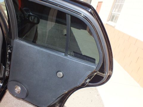 2003 Ford Crown Victoria - Rear door of a black sedan opened to show a custom carpet-covered panel with mounted speakers