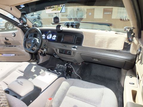 2003 Ford Crown Victoria - Wide cabin view of tan interior with carpeted dash top, center stack, floor shifter and overhead gauges
