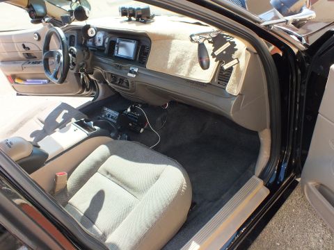 2003 Ford Crown Victoria - Passenger-side cabin view showing carpeted dash top, footwell and a mounted amplifier under the dash