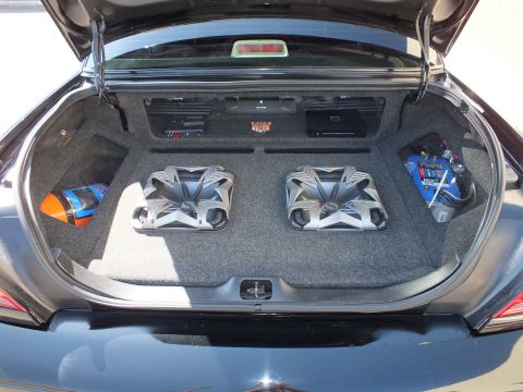 2003 Ford Crown Victoria - Trunk audio install showing two large subwoofers and a rack of amplifiers above on a carpeted panel
