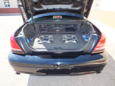 2003 Ford Crown Victoria - Rear view of an open trunk with two subwoofers and mounted amps in a custom carpeted enclosure