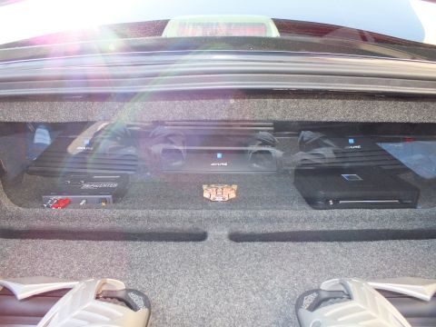 2003 Ford Crown Victoria - Close view of multiple Alpine amplifiers and a Soundstream unit mounted on a carpeted trunk shelf