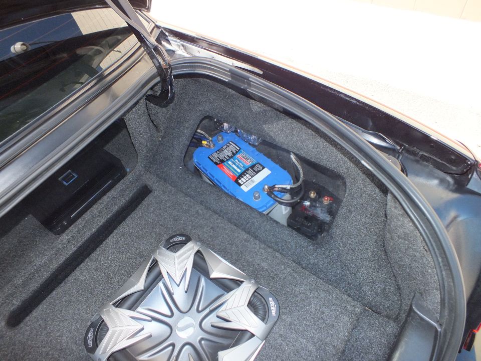 Trunk compartment with blue distribution block, fuses and chrome subwoofer