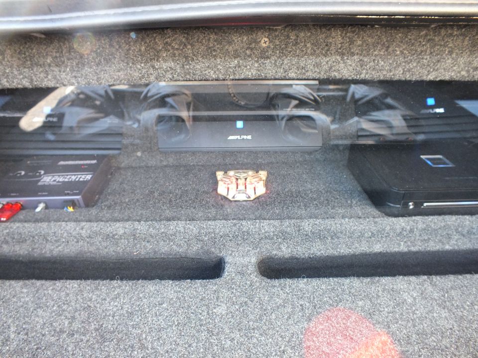Alpine amplifiers and Soundstream Epicenter mounted on carpeted trunk rack with Autobot emblem