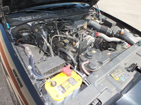 2003 Ford Crown Victoria - Worn engine compartment showing the alternator, battery and a yellow underhood information label