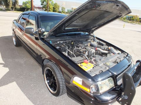 2003 Ford Crown Victoria - Front three-quarter of a black Crown Victoria with hood raised and dark machined-lip wheels