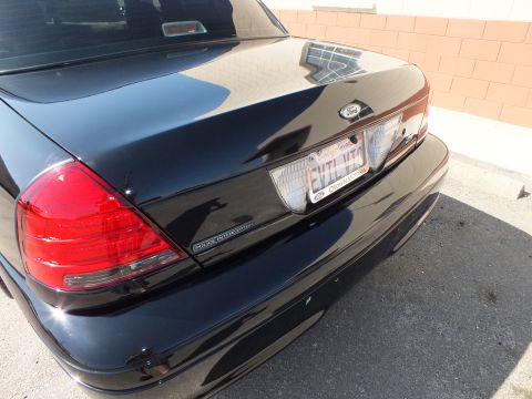 2003 Ford Crown Victoria - Trunk lid of a black Ford showing the Police Interceptor emblem and a plate reading EVIL VIC
