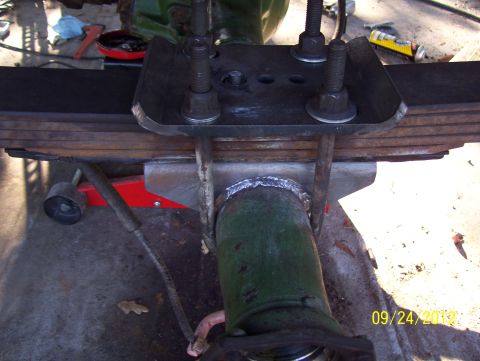 1990 Ford Bronco - Close-up of a vehicle's leaf spring and axle assembly, showing U-bolts and a mounting plate.