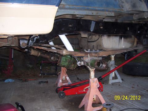 1990 Ford Bronco - The underside of a vehicle is shown elevated on jack stands for maintenance, likely, maintenance or repair work.