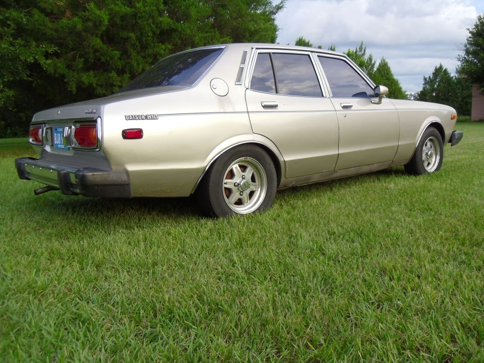 Gold 1978 Nissan Maxima sedan, rear 3/4 view, parked on grass