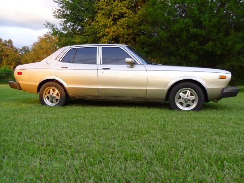 1978 Nissan Maxima - A two-tone sedan with chrome accents sits on a grassy lawn, viewed from its side profile.