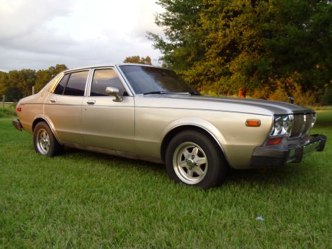 1978 Nissan Maxima - This 1978 Nissan Maxima sedan is parked on a grassy area with trees in the background.