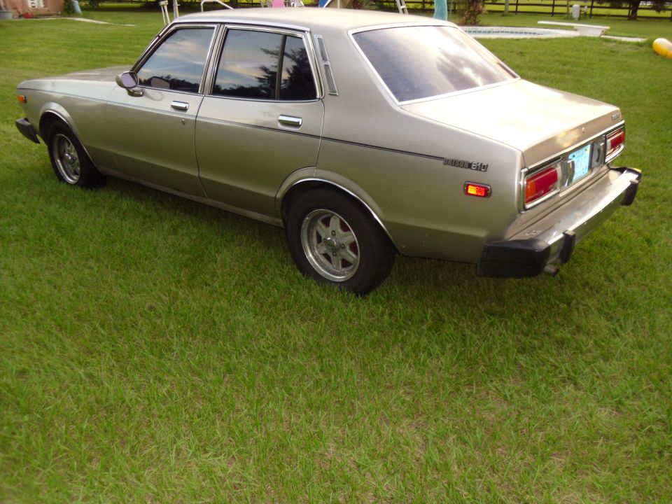 Gold 1978 Nissan Maxima sedan, 3/4 front view, parked on grass