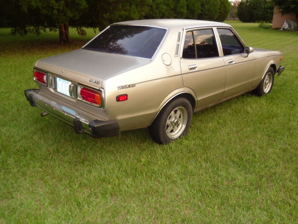 Gold 1978 Nissan Maxima sedan, rear 3/4 view, parked on grass