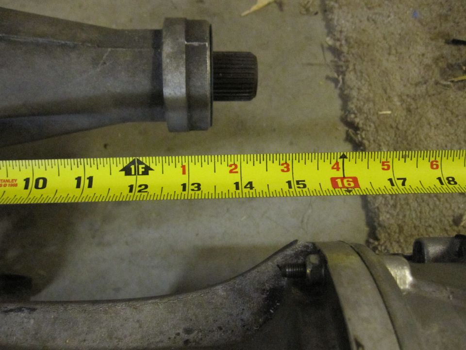 Close-up of a metal automotive differential housing with a yellow measuring tape showing approximately 16 inches