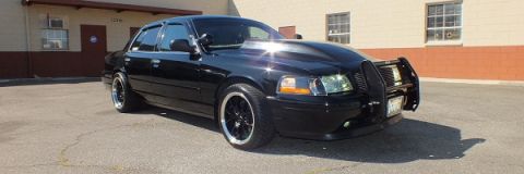 2003 Ford Crown Victoria - Front three-quarter of a lowered black Crown Victoria with push bar and dark multi-spoke wheels