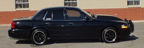 2003 Ford Crown Victoria - Side profile of a lowered black Crown Victoria sedan on dark wheels parked on asphalt