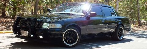 2003 Ford Crown Victoria - Front three-quarter of a black Crown Victoria with brush guard set against fall foliage