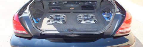 2003 Ford Crown Victoria - Black sedan trunk install showing twin subs, blue-accent amps and a Soundstream Epicenter unit