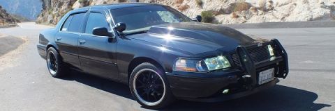 2003 Ford Crown Victoria - Front three-quarter of a black Crown Victoria with brush guard on a winding mountain pass