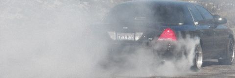 2003 Ford Crown Victoria - Rear of a black Ford laying down a smoky burnout, EVIL VIC plate and brake light glowing