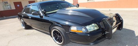 2003 Ford Crown Victoria - Front three-quarter of a black Crown Victoria with brush guard and dark multi-spoke wheels