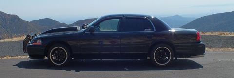 2003 Ford Crown Victoria - Profile of a black Crown Victoria with brush guard parked at a hilltop with mountain backdrop