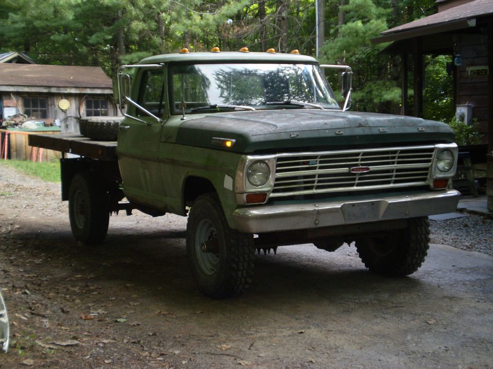 Ford F-Series truck with flatbed, parked outside a building