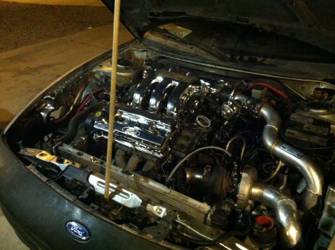 1993 Ford Probe - The engine bay of a car, a chrome intake manifold and a turbocharger. A Ford logo is visible on the valve cover.