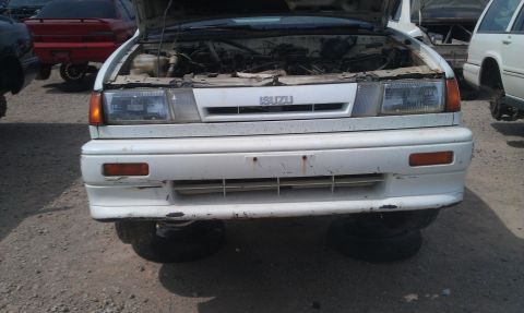 1991 Ford Festiva - This Isuzu Impulse is in a junkyard, with its hood open and resting on spare tires.