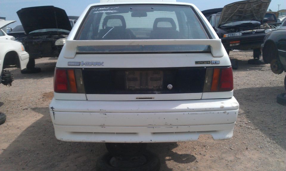 White hatchback with a rear spoiler and black panel between taillights