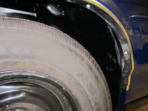 1991 Ford LTD Crown Victoria - Close-up view of a car's wheel well and tire, showing the black undercoating and tire details.