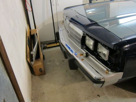 1991 Ford LTD Crown Victoria - The front grille and headlights of a Ford Crown Victoria are visible, parked indoors next to some stored items.