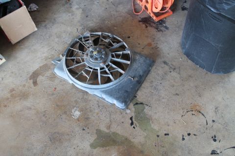 1990 Ford Bronco - A damaged radiator fan assembly is shown on the floor next to a trash can and a cardboard box.